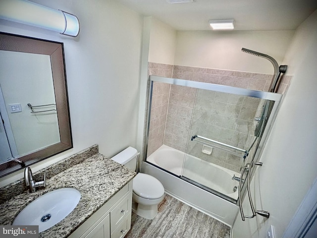 full bathroom featuring toilet, vanity, wood-type flooring, and shower / bath combination with glass door