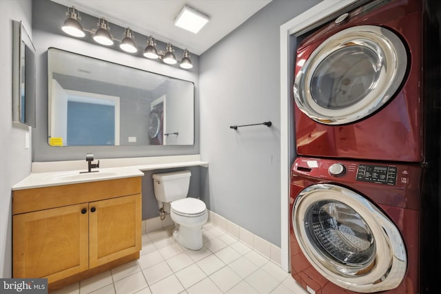 bathroom featuring toilet, vanity, tile patterned floors, and stacked washer and clothes dryer