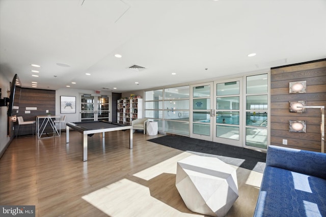 recreation room with french doors, hardwood / wood-style flooring, wooden walls, and pool table