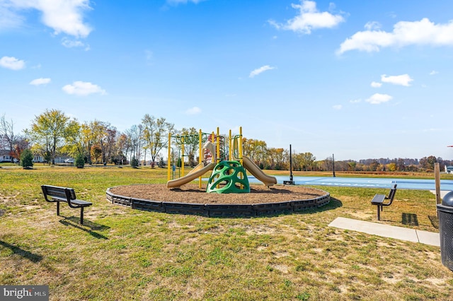 view of jungle gym featuring a lawn and a water view