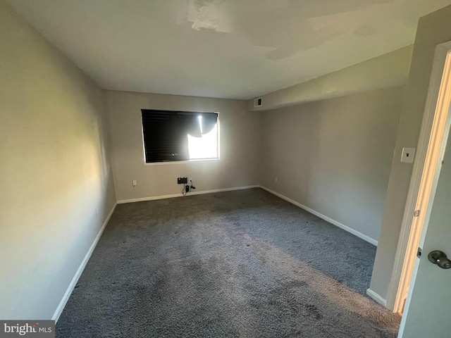 spare room featuring dark carpet