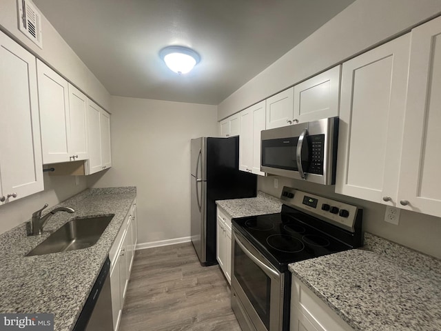 kitchen with white cabinetry, stainless steel appliances, light hardwood / wood-style flooring, and sink