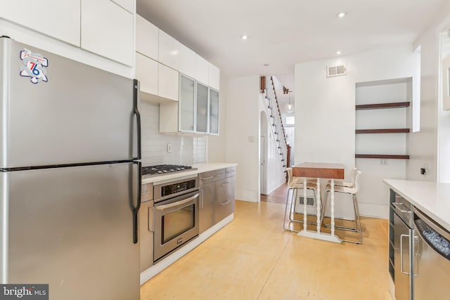 kitchen featuring white cabinetry, stainless steel appliances, and backsplash