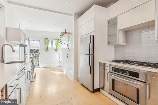 kitchen featuring appliances with stainless steel finishes, decorative backsplash, sink, and white cabinetry