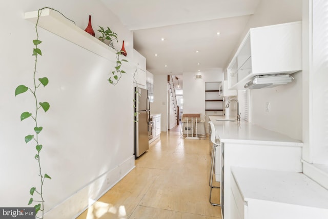 kitchen with sink, white cabinetry, and stainless steel refrigerator