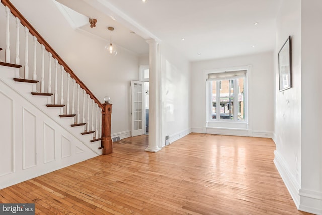 foyer entrance with ornate columns and light wood-type flooring