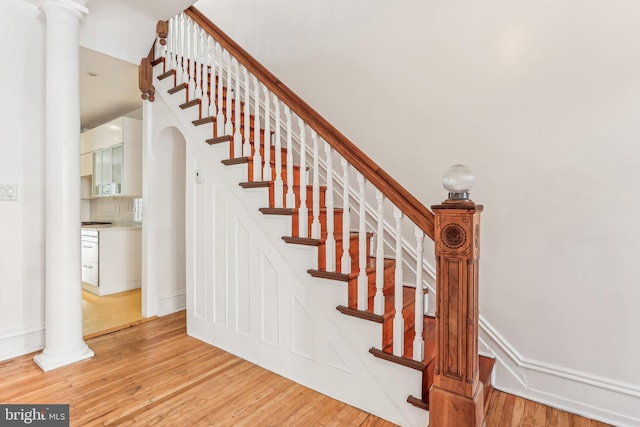 staircase featuring decorative columns and hardwood / wood-style flooring