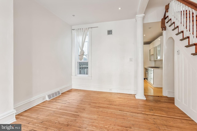 spare room with light hardwood / wood-style floors and decorative columns