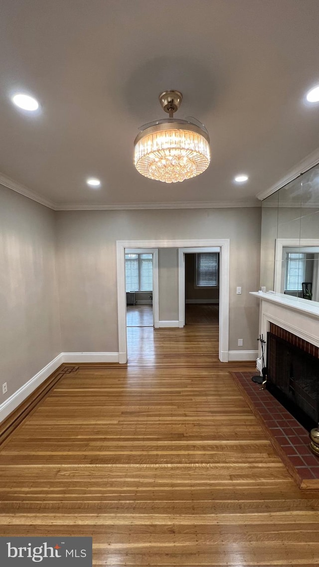 unfurnished living room featuring crown molding, a brick fireplace, and hardwood / wood-style flooring