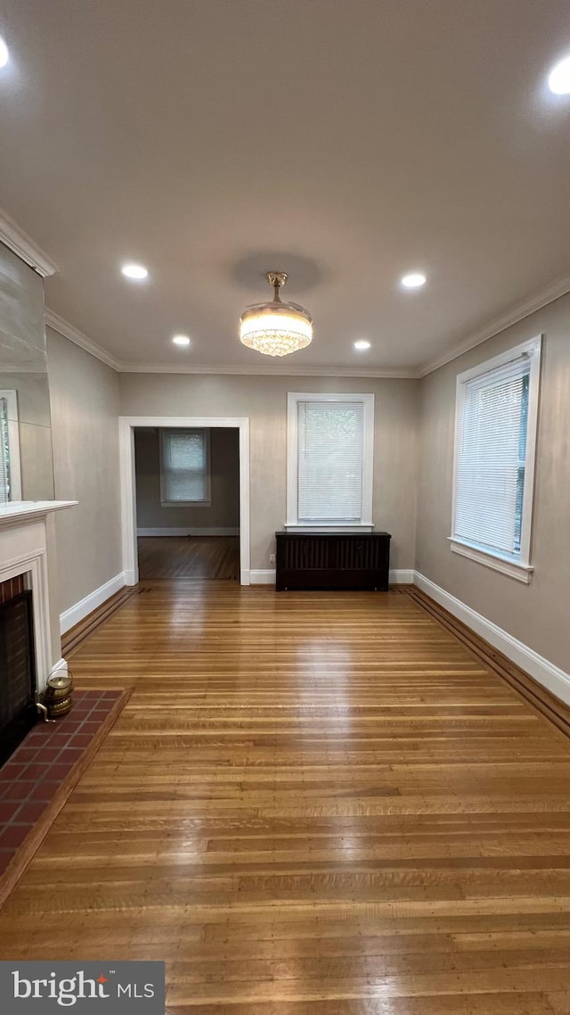 unfurnished living room with crown molding and hardwood / wood-style floors