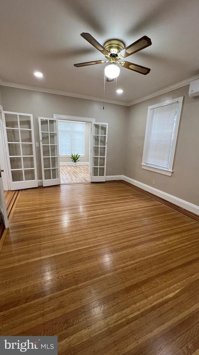 empty room featuring ornamental molding, a wall mounted AC, wood-type flooring, and ceiling fan