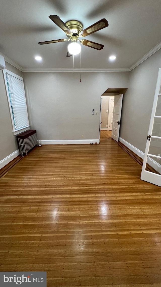 unfurnished room with radiator, ceiling fan, hardwood / wood-style flooring, and ornamental molding