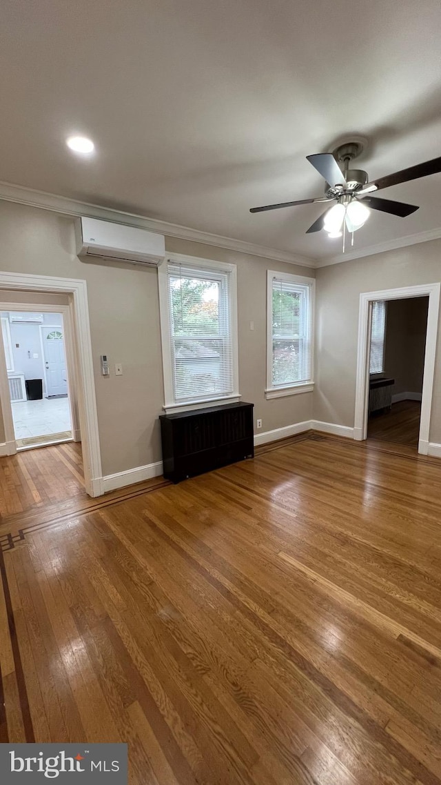 unfurnished room featuring ornamental molding, hardwood / wood-style flooring, an AC wall unit, and ceiling fan