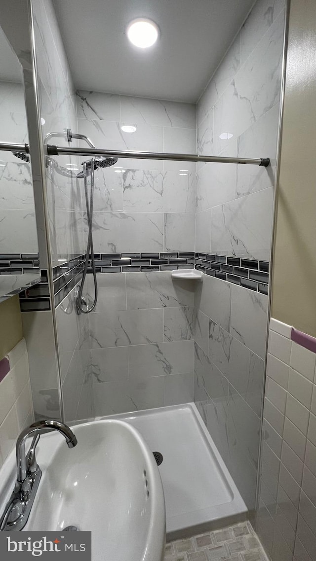 bathroom with tile walls, sink, and a tile shower