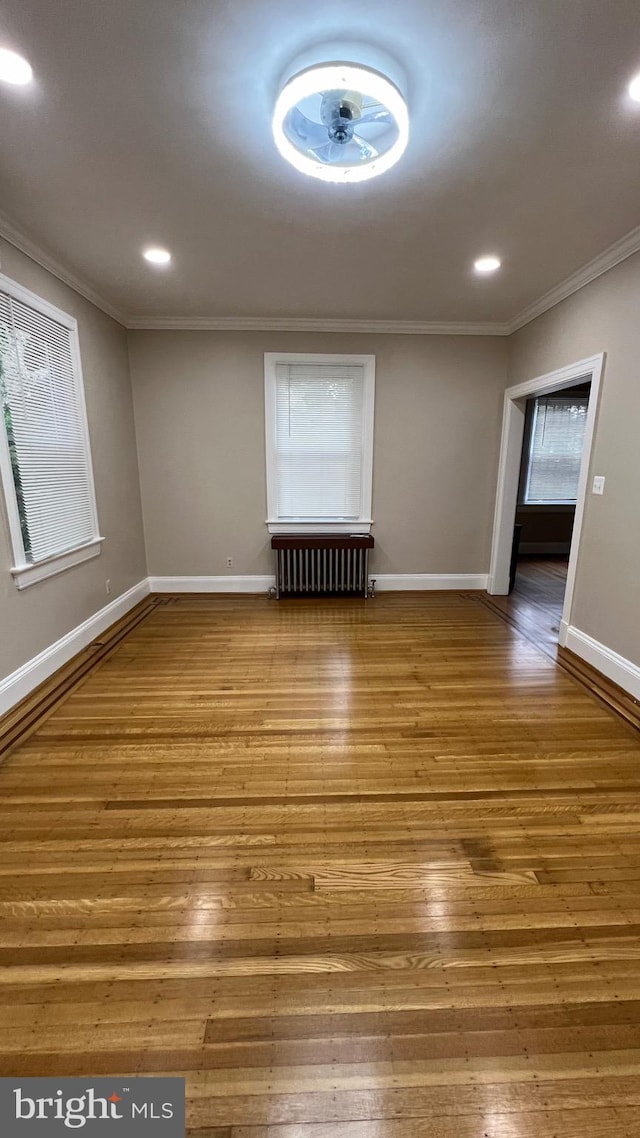 unfurnished room with crown molding, hardwood / wood-style flooring, and radiator heating unit