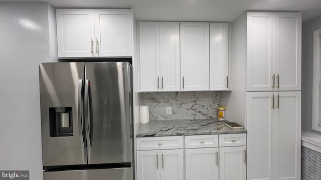 kitchen with white cabinetry, tasteful backsplash, dark stone counters, and stainless steel refrigerator with ice dispenser