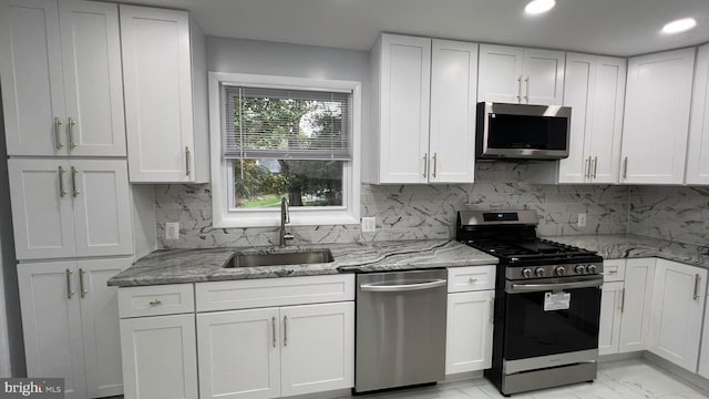 kitchen with sink, backsplash, stainless steel appliances, white cabinets, and light stone counters