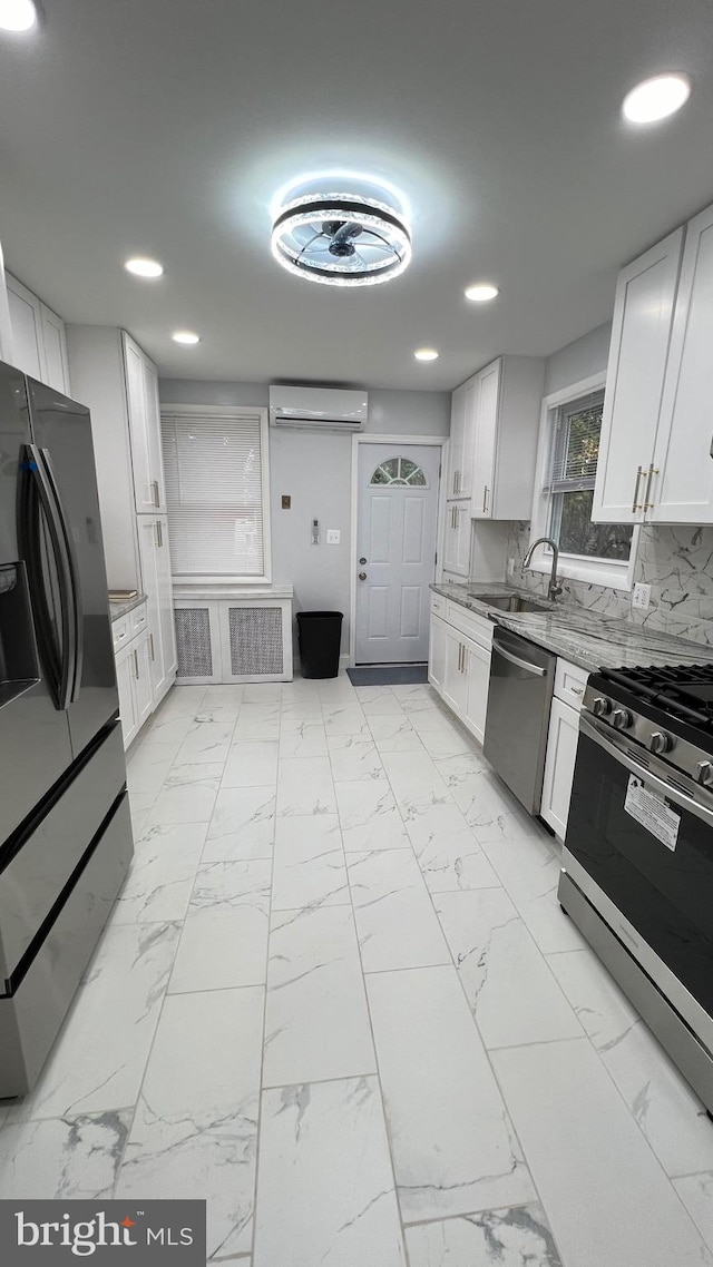 kitchen featuring white cabinetry, an AC wall unit, stainless steel appliances, and sink