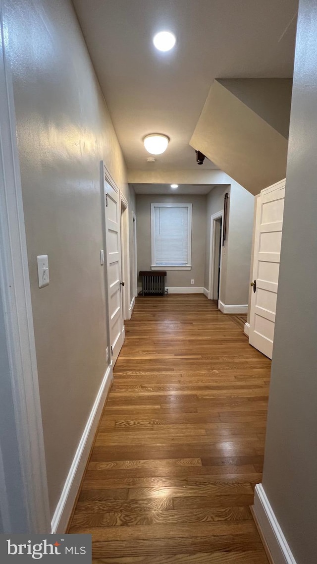 hallway with hardwood / wood-style flooring and radiator