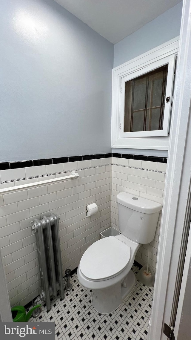 bathroom featuring toilet, radiator, tile walls, and tile patterned flooring