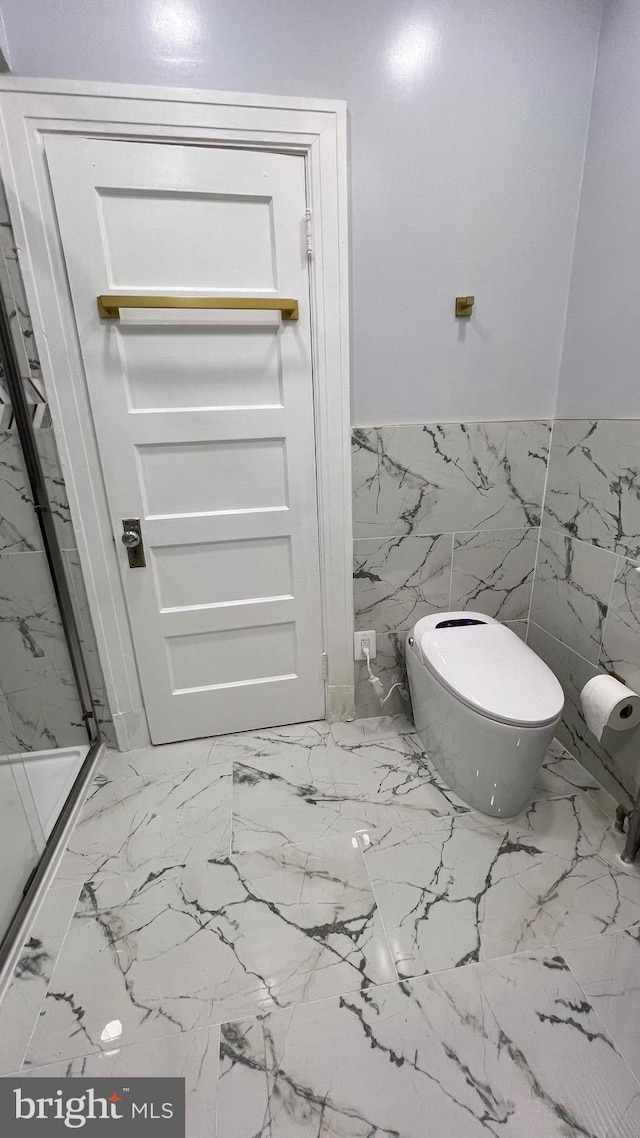 bathroom featuring toilet, tile walls, and a shower with door