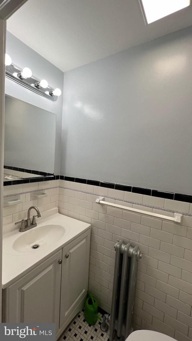 bathroom with vanity, tile patterned floors, tile walls, and radiator