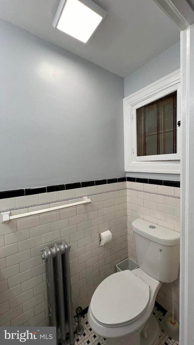 bathroom featuring radiator, toilet, tile walls, and tile patterned flooring