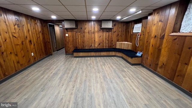 basement featuring light hardwood / wood-style flooring and wood walls