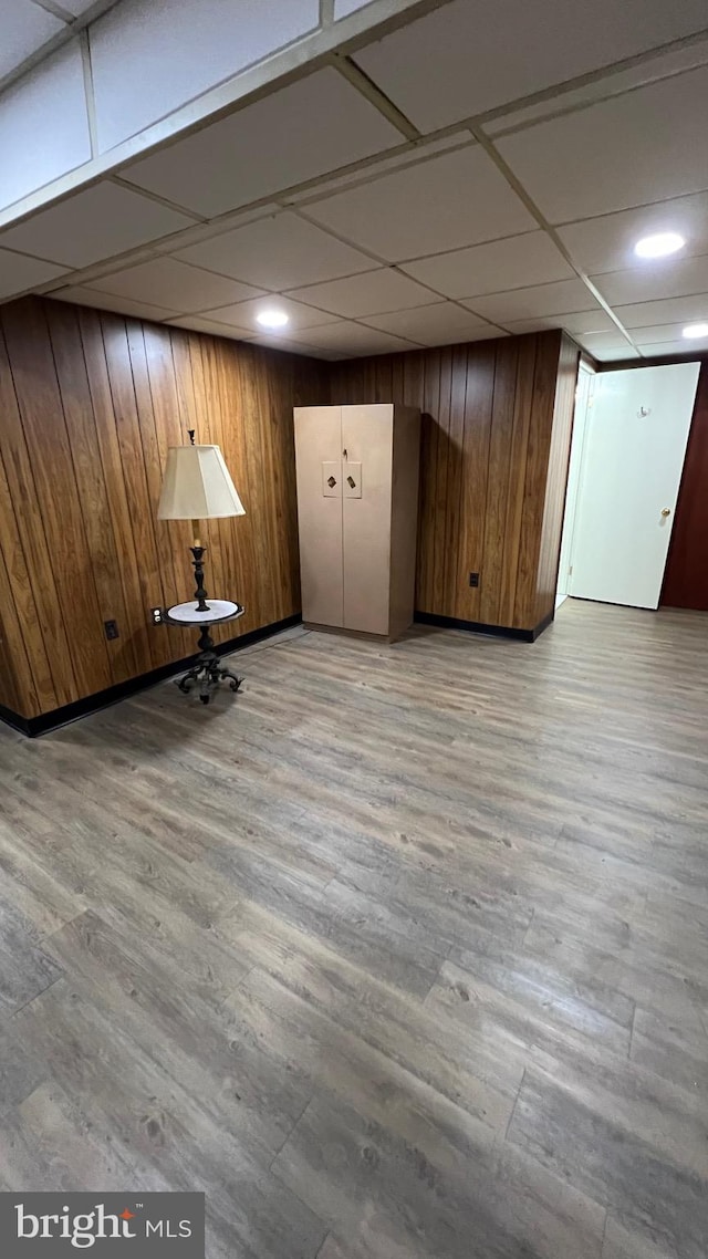 interior space featuring light hardwood / wood-style floors, wood walls, and a paneled ceiling