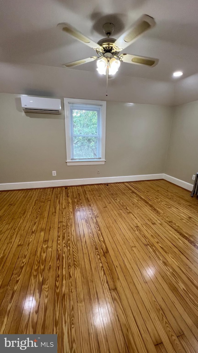 spare room with light hardwood / wood-style floors, an AC wall unit, and ceiling fan