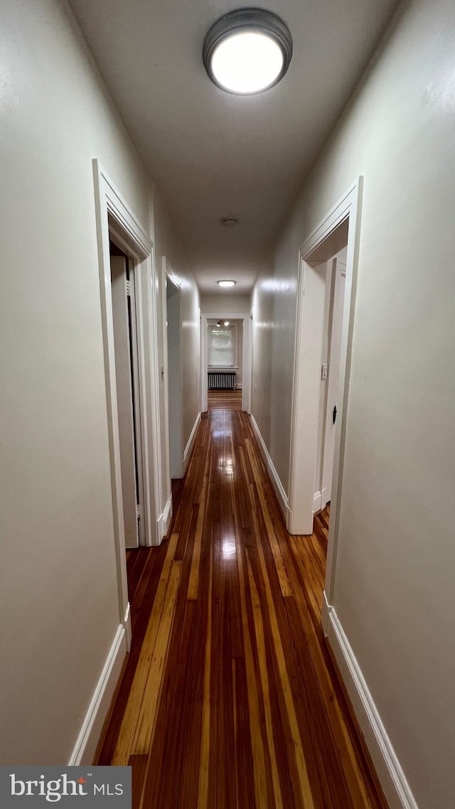 hallway with dark wood-type flooring and radiator heating unit