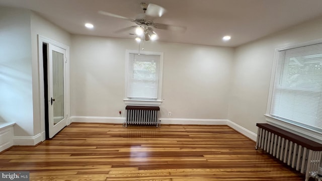 spare room featuring light hardwood / wood-style floors, radiator heating unit, and ceiling fan