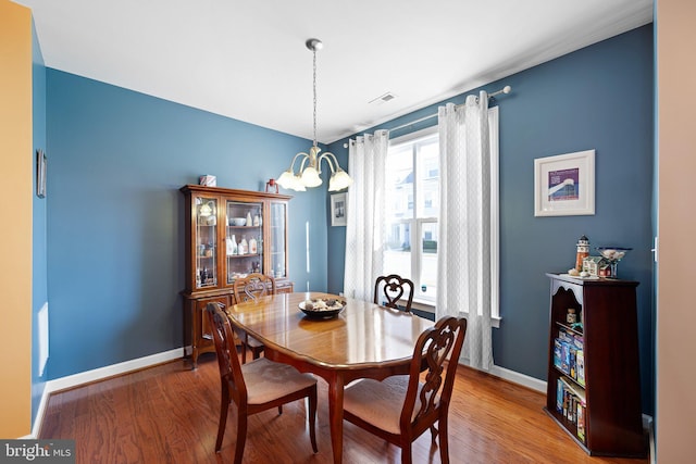 dining space with wood-type flooring and a notable chandelier