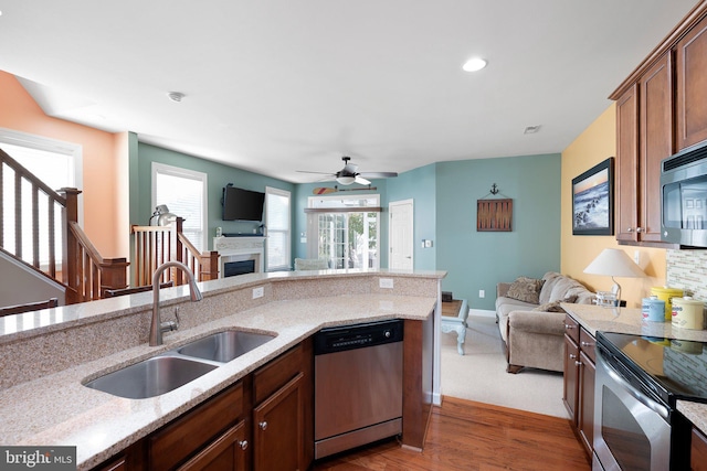 kitchen featuring appliances with stainless steel finishes, light stone counters, ceiling fan, sink, and dark hardwood / wood-style floors