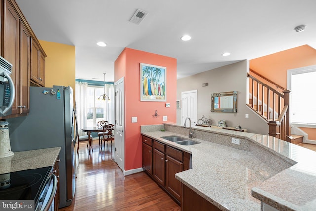 kitchen featuring light stone countertops, sink, hanging light fixtures, and dark wood-type flooring