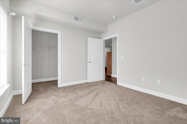 unfurnished bedroom featuring light carpet and a closet