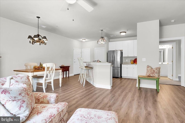 living room featuring light hardwood / wood-style floors and ceiling fan with notable chandelier