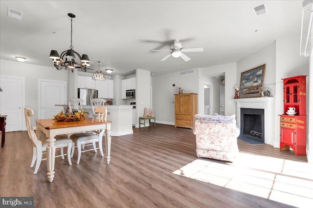 dining area with wood-type flooring and ceiling fan with notable chandelier