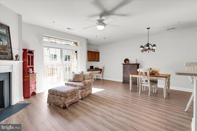 living room featuring ceiling fan with notable chandelier and hardwood / wood-style floors