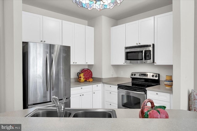 kitchen featuring appliances with stainless steel finishes, white cabinets, and sink