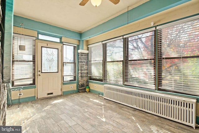 unfurnished sunroom with a wealth of natural light, ceiling fan, and radiator