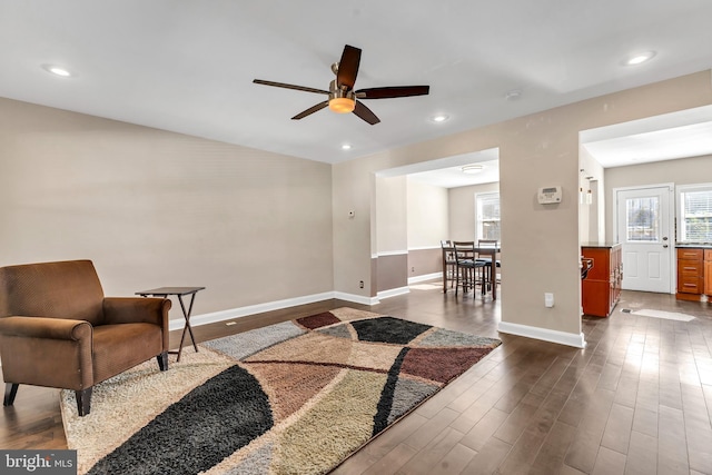 living area with ceiling fan and dark hardwood / wood-style flooring