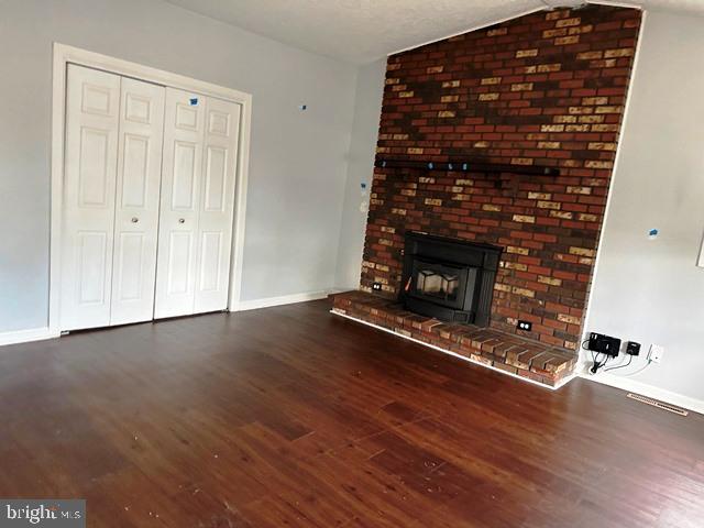 unfurnished living room with vaulted ceiling, a fireplace, and dark hardwood / wood-style floors