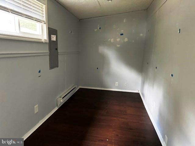 empty room with baseboard heating, electric panel, and dark hardwood / wood-style flooring