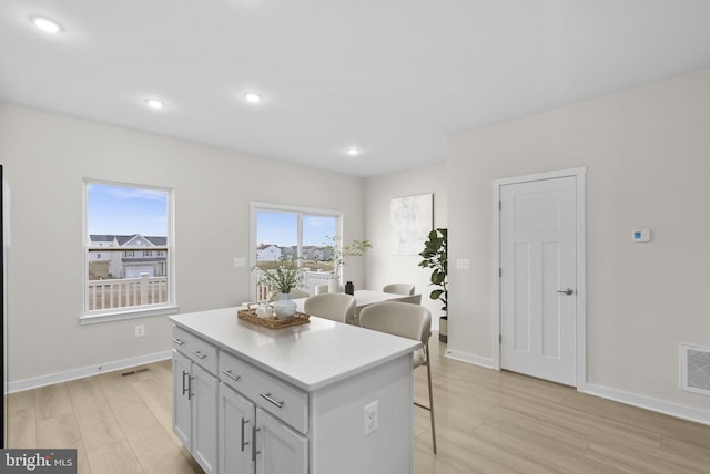 kitchen with a kitchen island, light wood-type flooring, and a breakfast bar