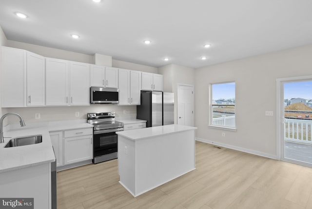 kitchen with appliances with stainless steel finishes, a center island, plenty of natural light, white cabinets, and sink