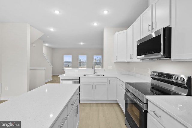 kitchen with light stone counters, stainless steel appliances, white cabinets, and sink