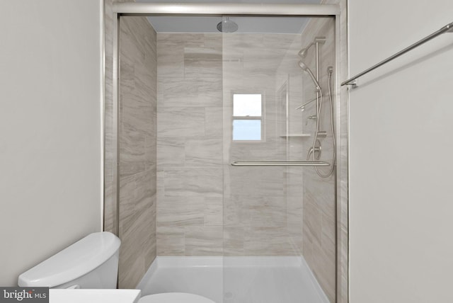 bathroom with a shower with shower door and toilet