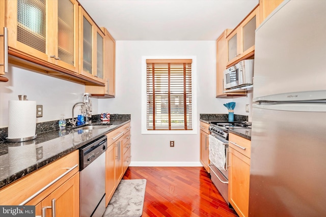 kitchen featuring sink, dark wood-type flooring, stainless steel appliances, and dark stone countertops