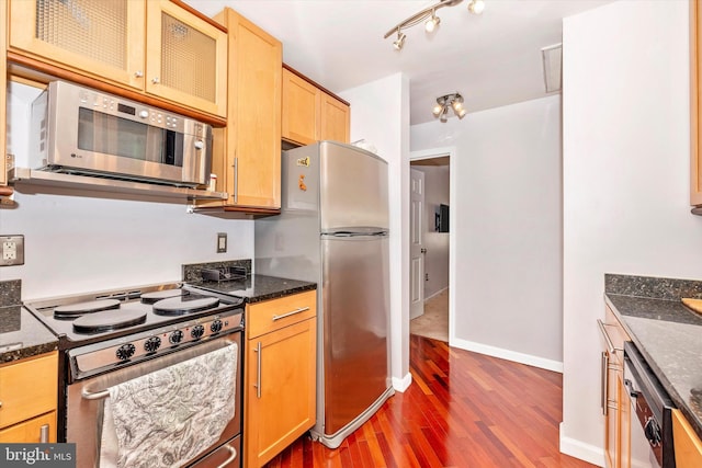 kitchen with hardwood / wood-style flooring, stainless steel appliances, and dark stone counters